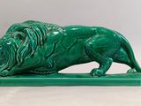 une image représentant une statue verte de lion posée sur un socle vert