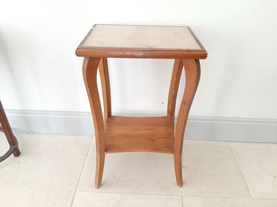 une petite table en bois avec un plateau en verre, posée sur un sol carrelé