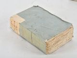 an old book sitting on a table next to a cell phone