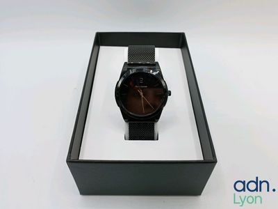 une image représentant une montre dans un écrin noir posé sur une surface blanche