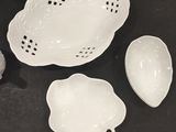 several white dishes and spoons on a table with a teddy bear