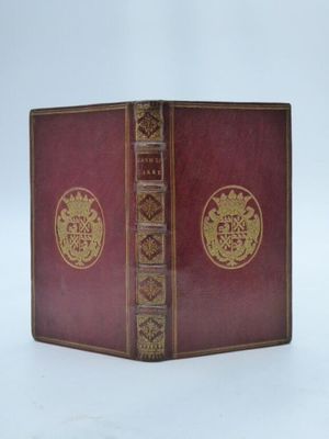 un vieux livre à la couverture rouge ornée d'un emblème doré