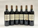 six bottles of wine are lined up on a white surface
