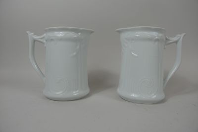 Deux brocs en faïence blanche à décor de feuillage stylisé.