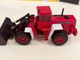 a red toy tractor and a black toy bulldozer on a white table