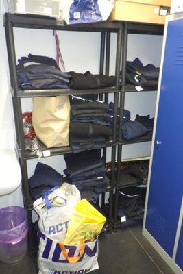 un casier bleu dans une pièce où se trouvent plein de vêtements