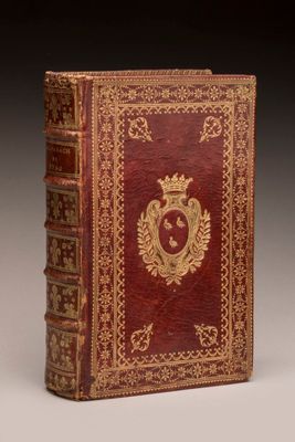 an old book with a red cover and gold decoration