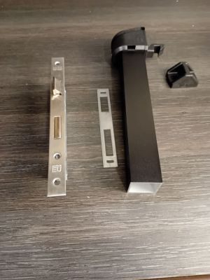 a black door handle and a metal latch on a wooden table