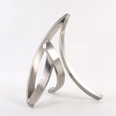 un gros plan d'une sculpture métallique posée sur une surface blanche