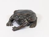 statue of a frog sitting on a white surface