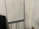 a white board in the corner of a room next to a black bag