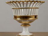gold and white glass vase with a gold rim on a wooden table