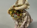 a figurine of a woman holding a basket of flowers