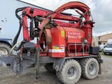 une grosse machine rouge garée sur la terre battue