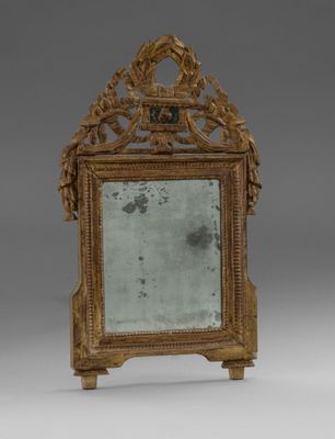 un miroir ancien doté d'un cadre doré et d'une décoration ouvragée dans sa partie supérieure