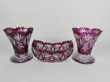 three purple glass vases sitting next to each other on a white surface