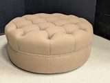 beige tufted round ottoman with studded trim