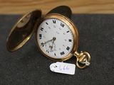 une montre de poche en or posée sur une table, à laquelle est attachée une étiquette