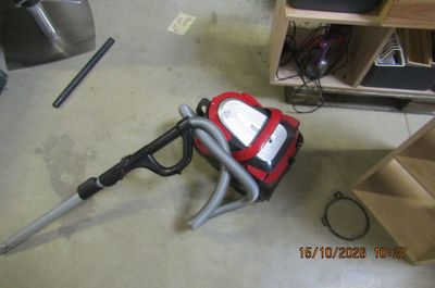 un aspirateur rouge et noir posé par terre dans une pièce
