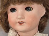 a close up of a doll with brown hair and blue eyes