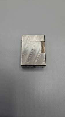 un gros plan sur un étui à cigarettes en argent posé sur une table