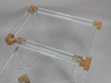 a clear glass table with two wooden legs on a white surface