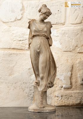 a statue of a woman that is standing next to a stone wall