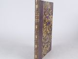 an old book with a purple cover sitting on top of a white surface