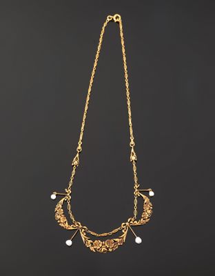 a gold necklace with pearls on a black background