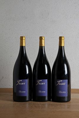 three bottles of wine are lined up on a wooden table