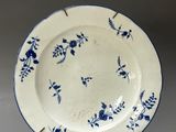 a blue and white plate on a stand on a gray surface