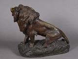 bronze statue of a lion on a rock on a gray background