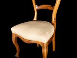 a wooden chair with a white upholstered seat on a black background