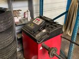 a tire changer in a garage next to a stack of tires
