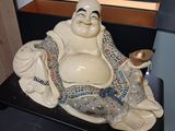 a statue of a smiling buddha sitting on top of a table