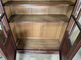 a wooden cabinet with a glass door and shelves