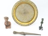 a gold plate with a decorative design on it next to a small figurine