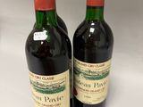 two bottles of red wine sitting next to each other on a table