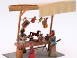 figurines of people sitting at a table in front of a wooden structure