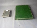 a small green book and a small silver box on a table