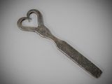 a metal spoon with a heart shaped handle on a white surface