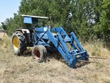 a blue tractor that is parked in the grass