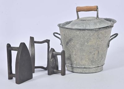 un seau en métal muni d'une poignée en bois, à côté d'une paire d'outils en fer
