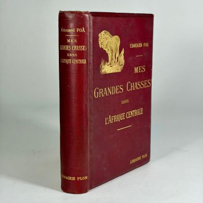 an old book sitting on a white surface with a red cover