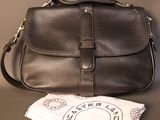 brown leather purse on table next to a white bag and a pair of scissors