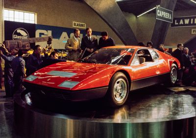 des personnes rassemblées autour d'une voiture de sport rouge exposée