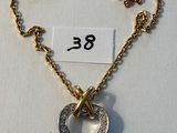 collier composé d'un cœur et d'une croix suspendus à une chaîne, sur laquelle est accrochée une étiquette de prix