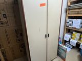 une armoire blanche dans une pièce où se trouvent des cartons par terre