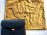 a black purse with a chain hanging from it next to a pouch