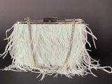 a close up of a white purse with feathers on a black background